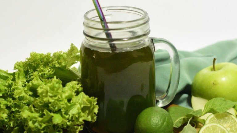 Jarra de zumo verde recien hecho junto a lechuga, manzana verde y limas